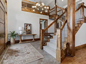 Entryway featuring a towering ceiling, light wood-type flooring, and an inviting chandelier