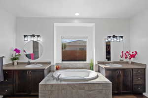 Bathroom with vanity and tiled tub