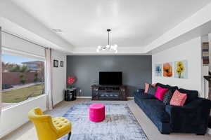 Carpeted living room with a raised ceiling and a notable chandelier