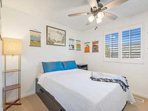 Bedroom with ceiling fan and light colored carpet