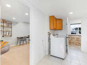 Laundry area featuring washer and dryer, cabinets, and light tile patterned floors