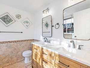 Bathroom with vanity, toilet, and tile walls