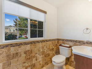 Bathroom with vanity, toilet, and tile walls