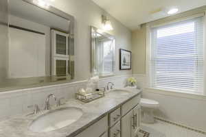 Bathroom with tile patterned flooring, vanity, tile walls, and toilet