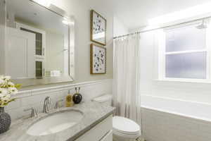 Full bathroom with toilet, vanity, and shower / tub combo with curtain