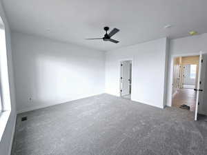 Unfurnished bedroom with dark colored carpet and ceiling fan