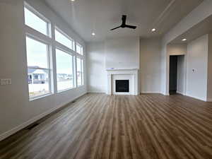 Unfurnished living room with dark hardwood / wood-style floors, ceiling fan, and a tiled fireplace