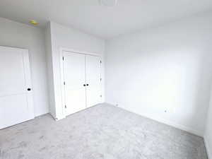 Unfurnished bedroom featuring light colored carpet and a closet