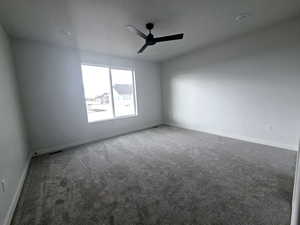 Unfurnished room with ceiling fan and dark carpet