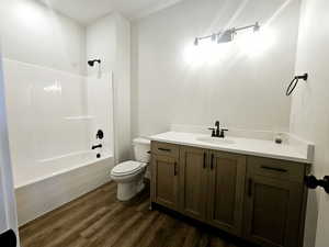 Full bathroom with vanity, shower / bathtub combination, toilet, and wood-type flooring