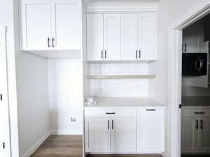 Bar featuring backsplash and white cabinetry