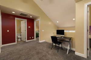 Office space with lofted ceiling and dark colored carpet