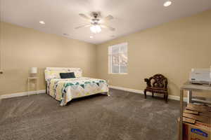 Bedroom featuring ceiling fan and dark colored carpet