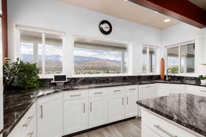 Kitchen featuring light wood-type flooring, white cabinets, sink, dark stone countertops, and a mountain view