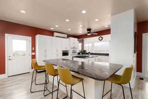 Kitchen featuring white cabinets, a wealth of natural light, a kitchen island, and a wall unit AC