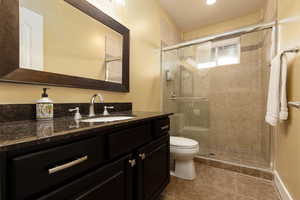 Bathroom featuring tile patterned flooring, vanity, a shower with door, and toilet