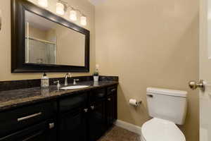 Bathroom featuring tile patterned flooring, vanity, toilet, and an enclosed shower