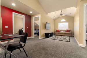 Carpeted living room featuring ceiling fan and vaulted ceiling