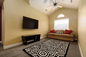 Carpeted living room featuring ceiling fan and lofted ceiling