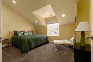 Bedroom with dark colored carpet and vaulted ceiling