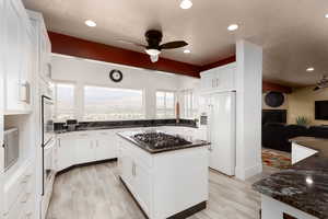 Kitchen featuring white cabinets, a center island, light wood-type flooring, and white appliances