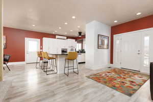 Foyer featuring plenty of natural light, ceiling fan, light wood-type flooring, and a wall unit AC