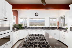 Kitchen featuring a mountain view, white double oven, white cabinetry, and dark stone countertops