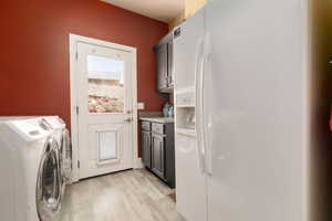 Clothes washing area with cabinets, independent washer and dryer, and light wood-type flooring