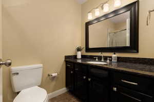 Bathroom featuring toilet, vanity, tile patterned floors, and a shower with door