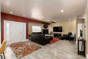 Living room featuring ceiling fan, light hardwood / wood-style floors, and a textured ceiling