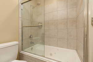 Bathroom with toilet and enclosed tub / shower combo