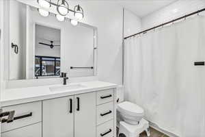 Bathroom with vanity, toilet, ceiling fan, and curtained shower