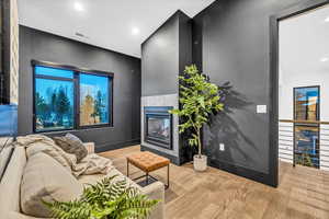 Living room with light hardwood / wood-style floors and a tiled fireplace