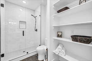 Bathroom featuring tile patterned flooring, toilet, and a shower with shower door