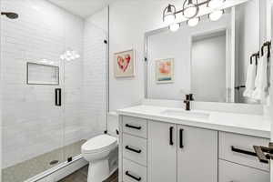 Bathroom featuring tile patterned floors, vanity, a shower with shower door, and toilet