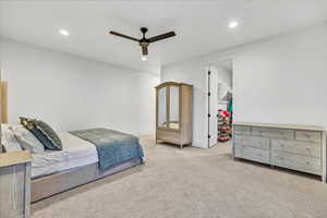 Carpeted bedroom featuring ceiling fan, a spacious closet, and a closet