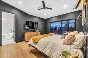 Bedroom with ceiling fan, light wood-type flooring, and ensuite bath