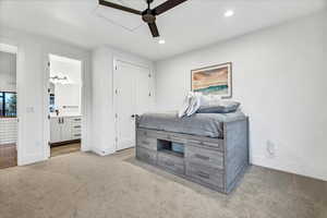 Carpeted bedroom featuring ensuite bathroom and ceiling fan