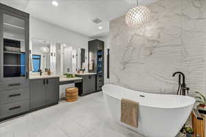 Bathroom featuring a bathing tub, vanity, and tile walls