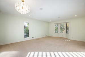 Carpeted spare room with a notable chandelier and ornamental molding