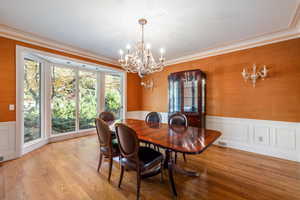 Dining space with an inviting chandelier, ornamental molding, and light hardwood / wood-style flooring