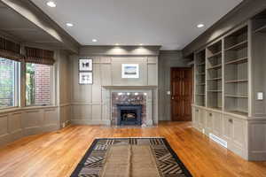 Unfurnished living room with light wood-type flooring, built in features, and ornamental molding