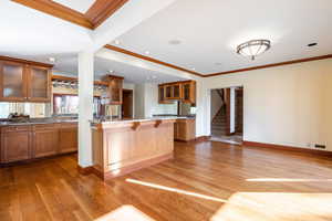 Kitchen with sink, light hardwood / wood-style floors, a kitchen bar, and crown molding