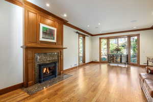 Unfurnished living room with a premium fireplace, light hardwood / wood-style flooring, and crown molding