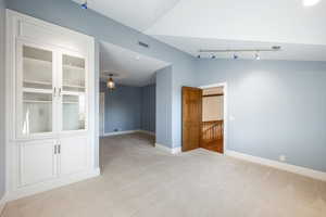 Spare room featuring light carpet and vaulted ceiling