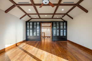 Spare room featuring lofted ceiling with beams and hardwood / wood-style flooring