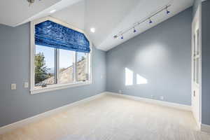 Unfurnished room featuring light colored carpet and vaulted ceiling