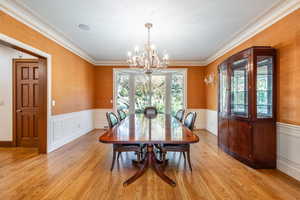 Dining space featuring a notable chandelier, light wood-type flooring, and crown molding