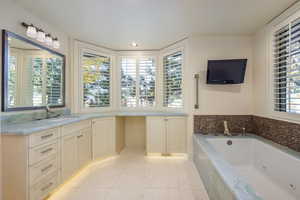 Bathroom featuring tile patterned flooring, vanity, and tiled tub