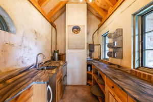 Bar featuring butcher block counters, sink, a wealth of natural light, and vaulted ceiling